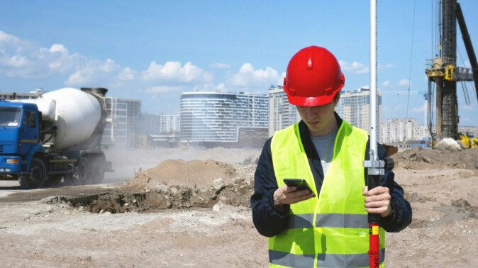 Land surveyor with total station representing the Preliminary Works node in the AllBIMclass BIM classification system